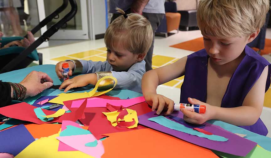 two children create art with bright colorful paper