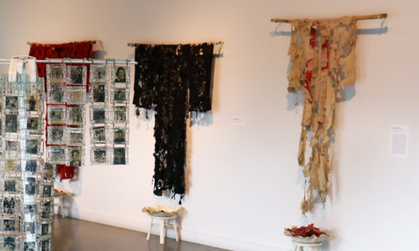 Kimono-style sculptures of different textures and made from different materials hang in a white gallery.