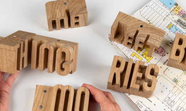 Block letters with hands and a map on a table.