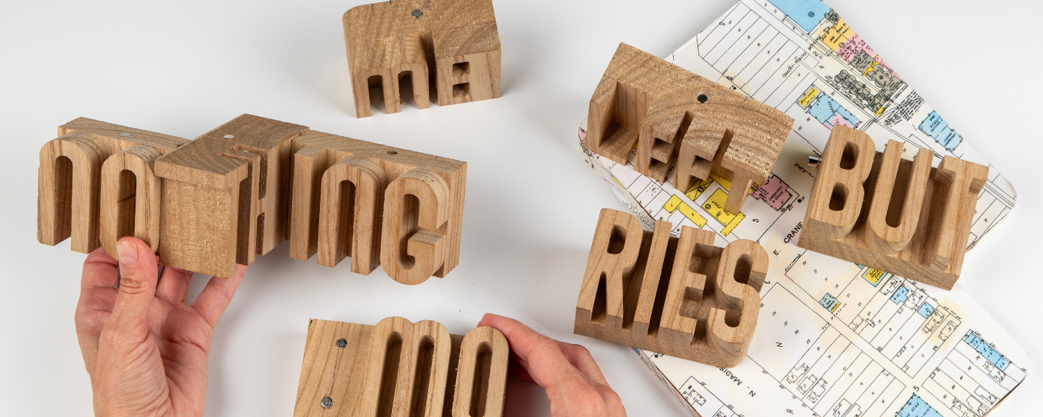 Block letters with hands and a map on a table.