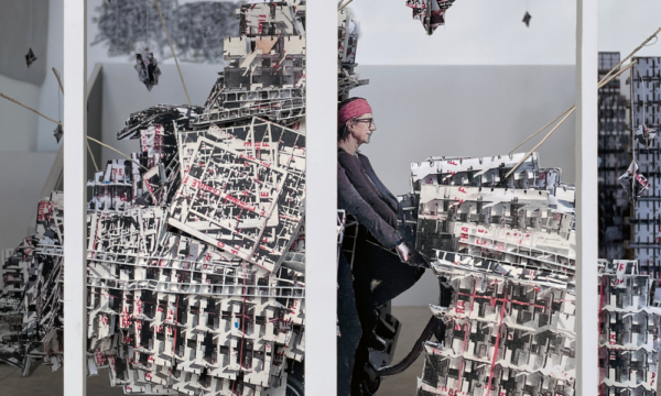 Installation art exhibition seen through a gallery window with bicycle, training wheels, laser cut packing boxes.