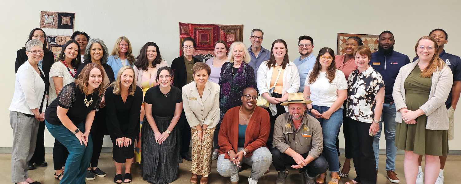 A diverse large group of people pose together for a group photo.