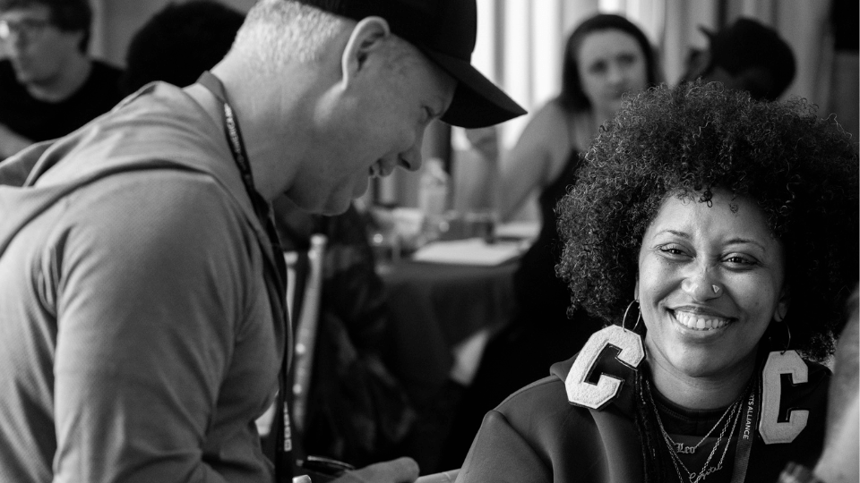 A man and woman smile and laugh together at a table.