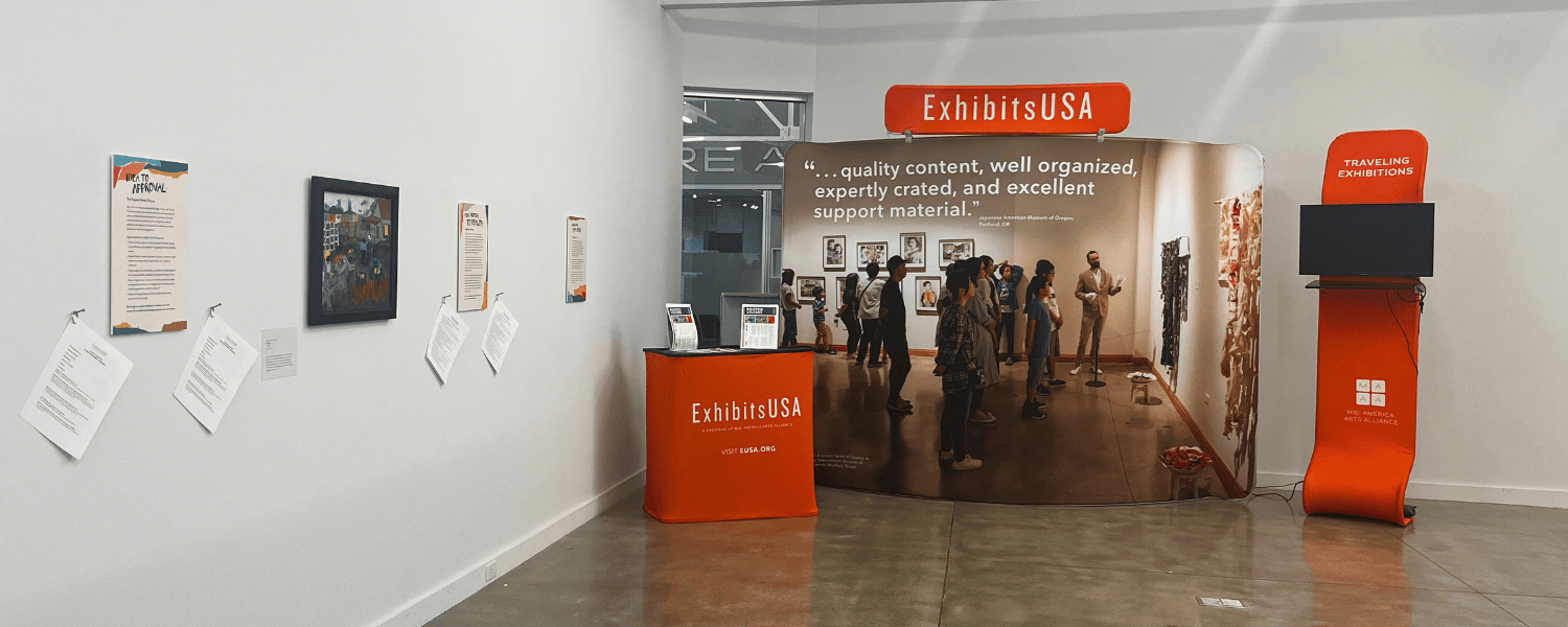 A banner stand that says ExhibitsUSA along with artwork on a gallery wall.