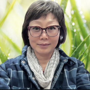 Portrait of EunKyung Jeong with a flannel shirt and grass background.