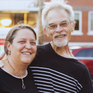 A woman and man stand together smiling.