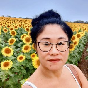 Portrait of Andi Meyer with sunflowers in the background.