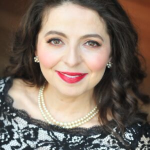 Portrait of Victoria Botero wearing a black lace top and pearls.