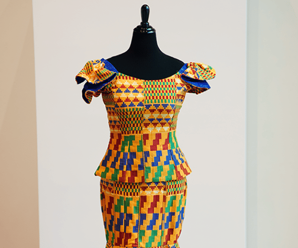 Intricately detailed woven patterns are visible on a woman's dress displayed on a model form.